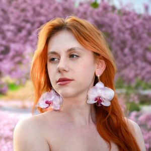 Kolczyki z prawdziwą orchideą w transparentnej oprawie migoczące w świetle, przypominające krople rosy.